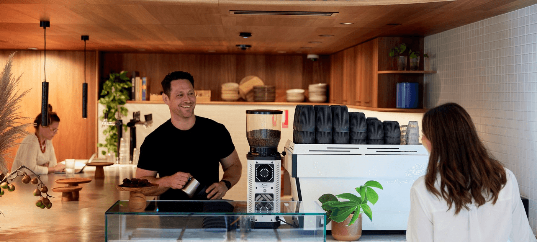 Barista serving a customer with a Huskee coffee cup